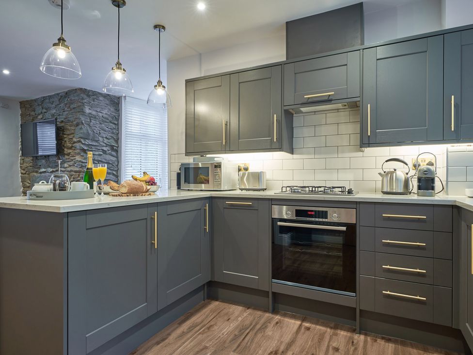 A kitchen with gray cabinets white countertops and a tiled backsplash at Lower Sheriff's Place in Windermere