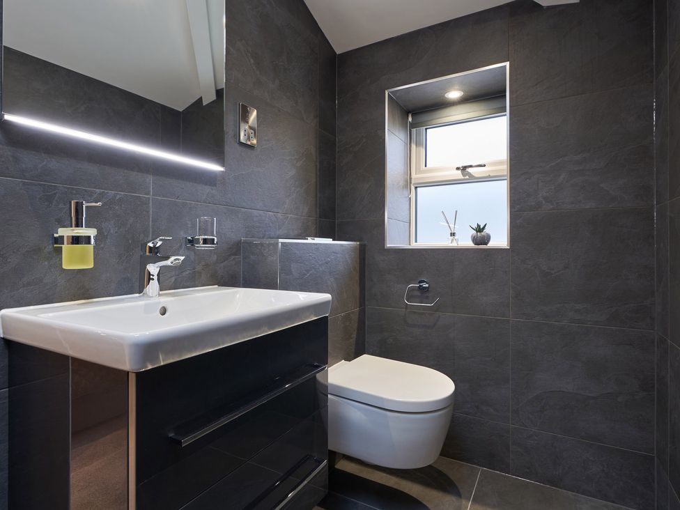 A bathroom with a sink and cabinet a toilet and a window at Lower Sheriff's Place in Windermere