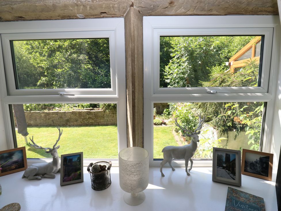A window with deer figurines and photographs at Springhead Cottage in Haworth