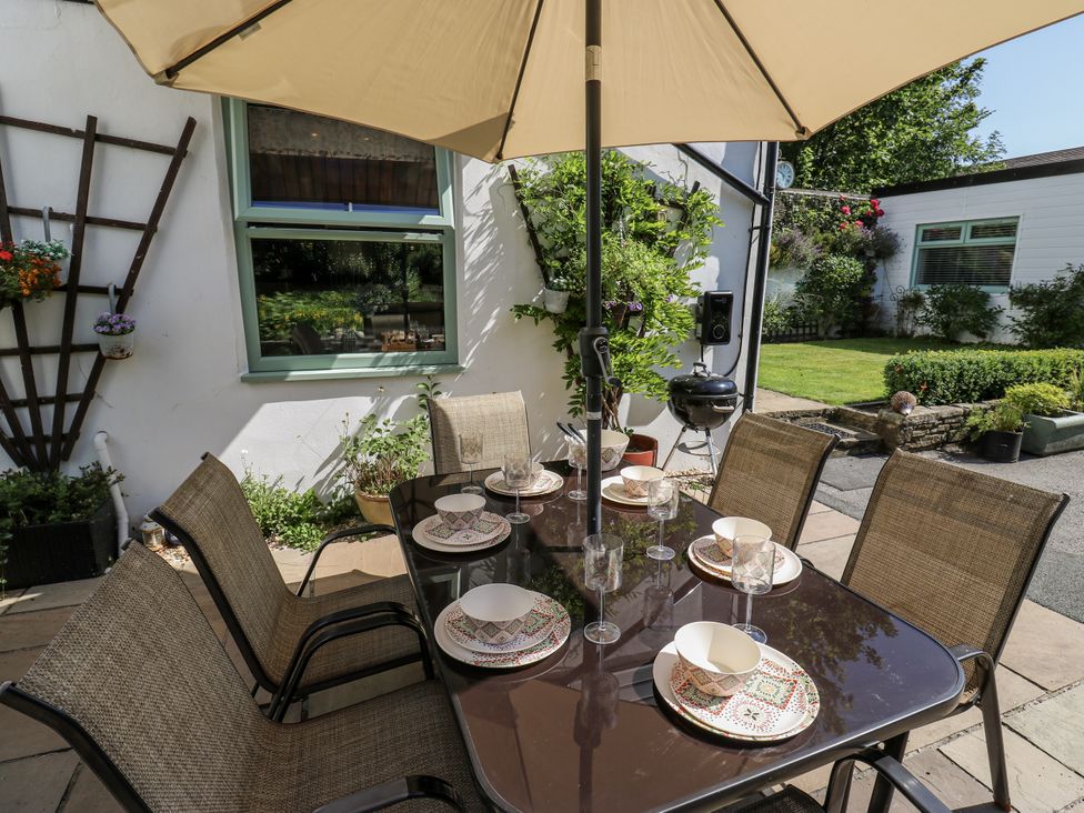 An outdoor dining area with a table and chairs at Springhead Cottage in Haworth