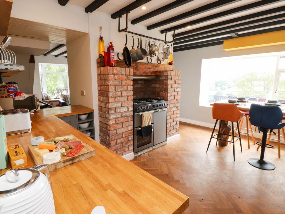 A kitchen with a stove and bar stools at Tyddyn Elidir near Old Colwyn