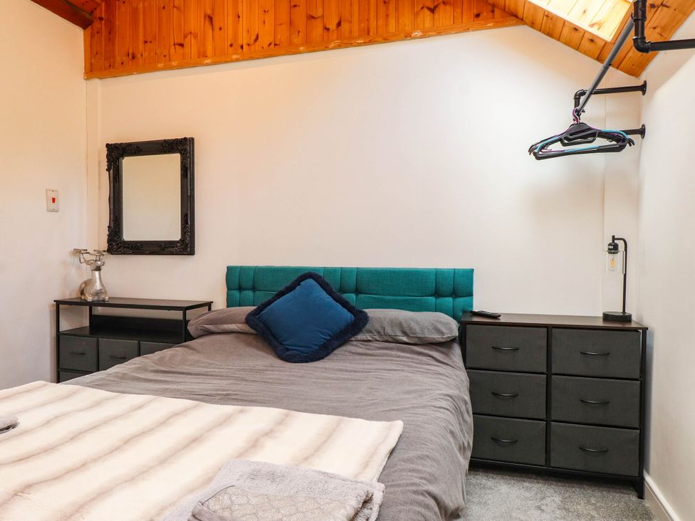 A bedroom with a bed, nightstand, and mirror at Tyddyn Elidir near Old Colwyn