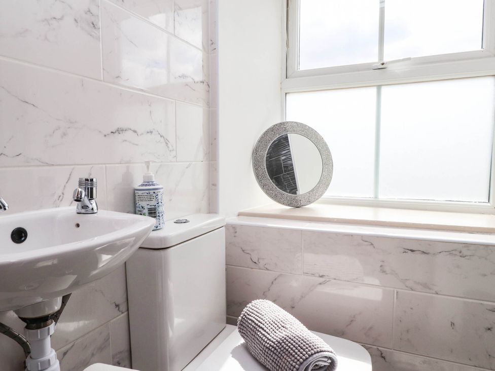 A bathroom with a toilet, sink, mirror, and towel at Tyddyn Elidir near Old Colwyn