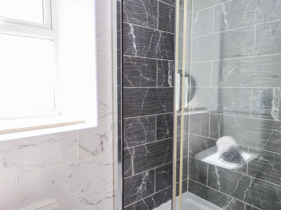 A bathroom with a shower and towel shelf at Tyddyn Elidir near Old Colwyn