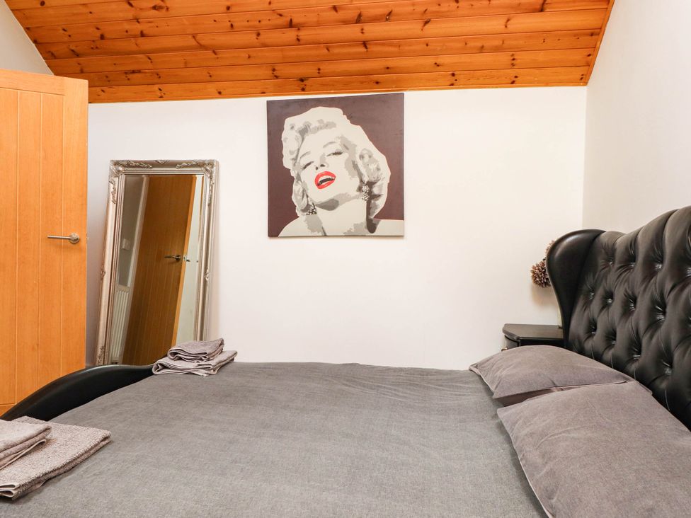 A bedroom with a bed and a mirror at Tyddyn Elidir near Old Colwyn