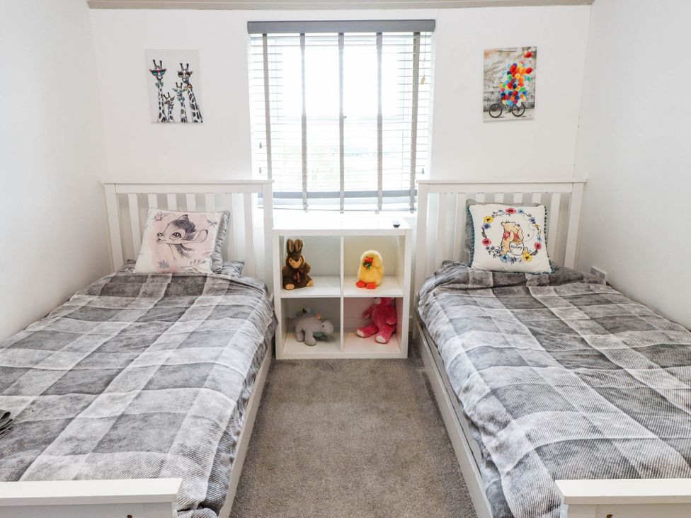 A bedroom with two beds and a shelf with toys at Tyddyn Elidir near Old Colwyn