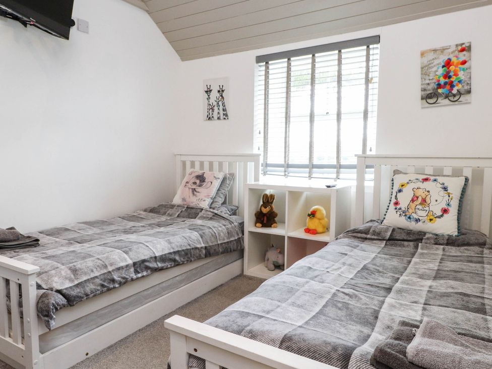 A bedroom with two beds and a shelf at Tyddyn Elidir near Old Colwyn