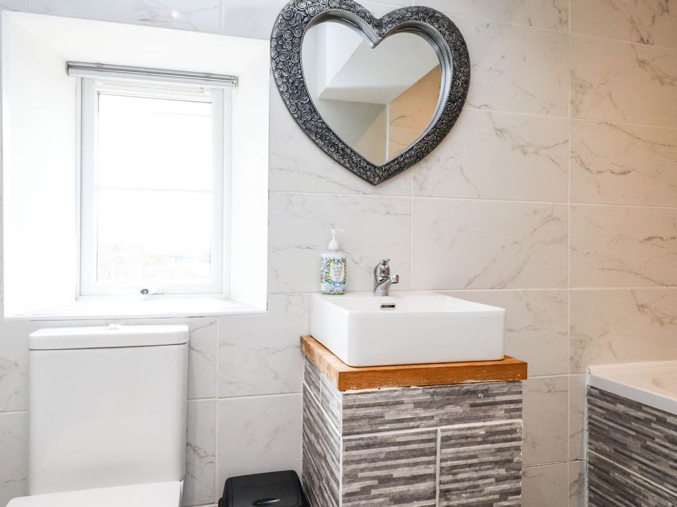 A bathroom with a sink, toilet, and mirror at Tyddyn Elidir near Old Colwyn