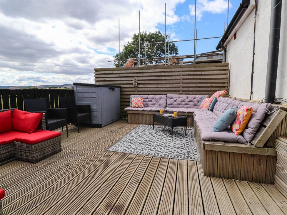An outdoor seating area with a table and cushions at Tyddyn Elidir near Old Colwyn