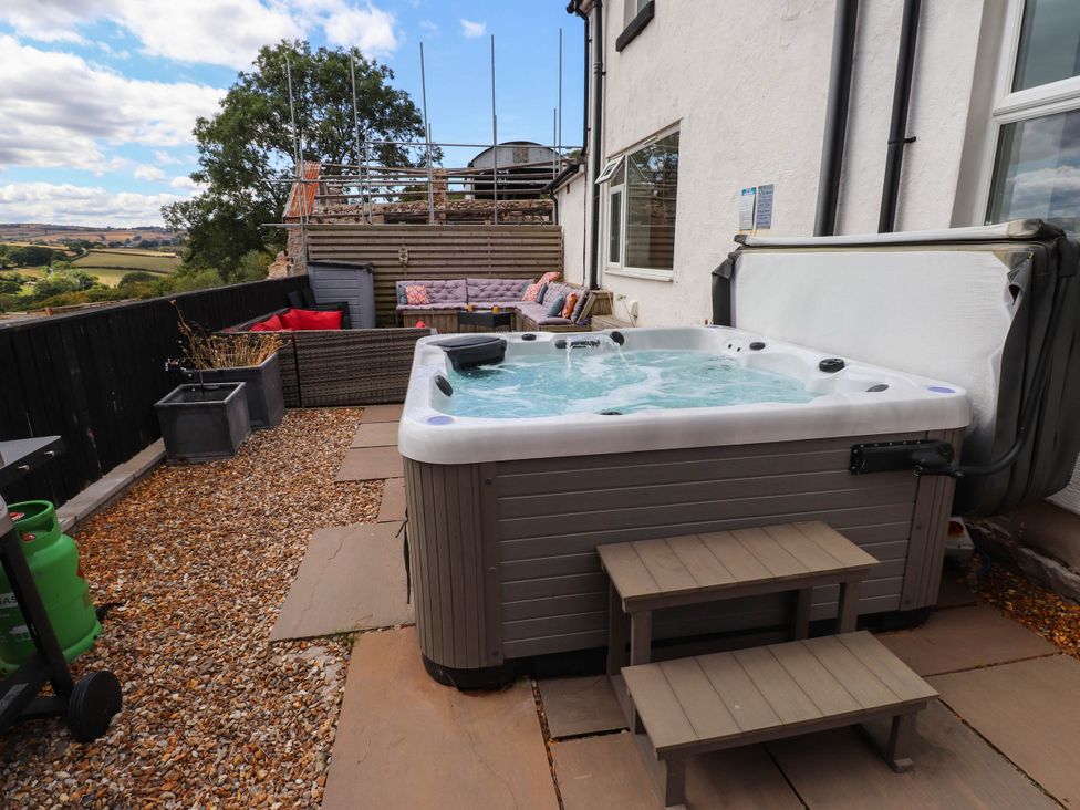 An outdoor space with a hot tub and seating area at Tyddyn Elidir near Old Colwyn