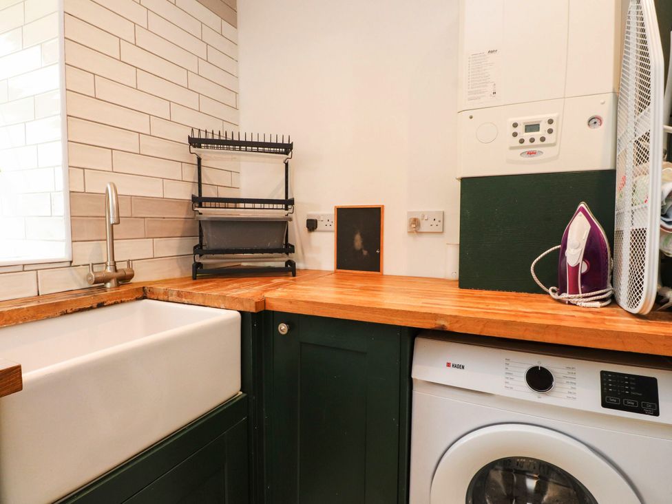 A laundry room with a sink and washing machine at Tyddyn Elidir near Old Colwyn