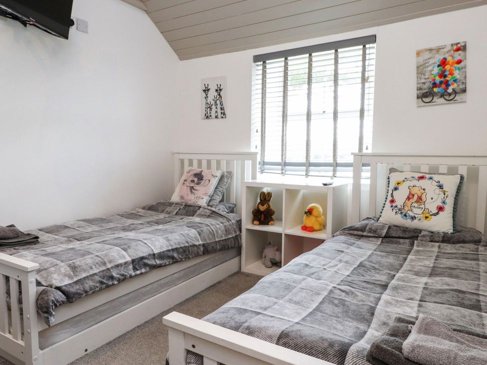 A bedroom with two beds and a shelf containing toys at Tyddyn Elidir near Old Colwyn