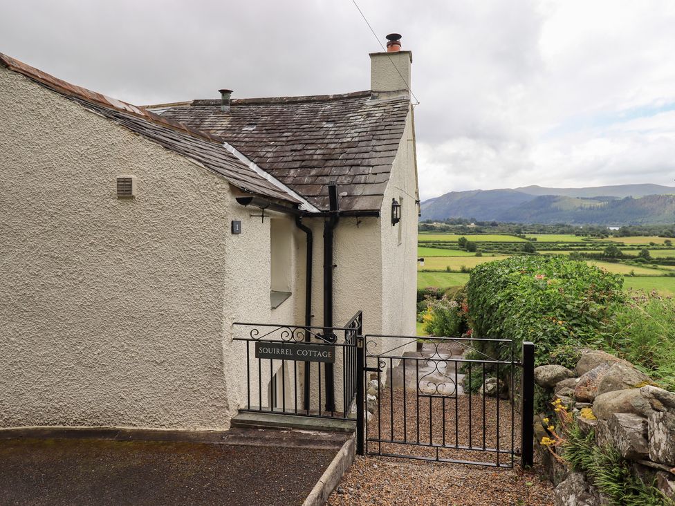 An outdoor view of Squirrel Cottage with garden and mountains in Bassenthwaite