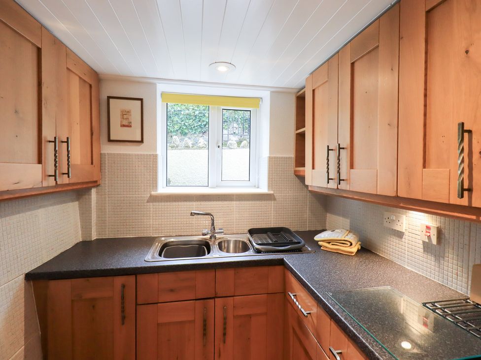 A kitchen with wooden cupboards and a sink at Squirrel Cottage in Bassenthwaite