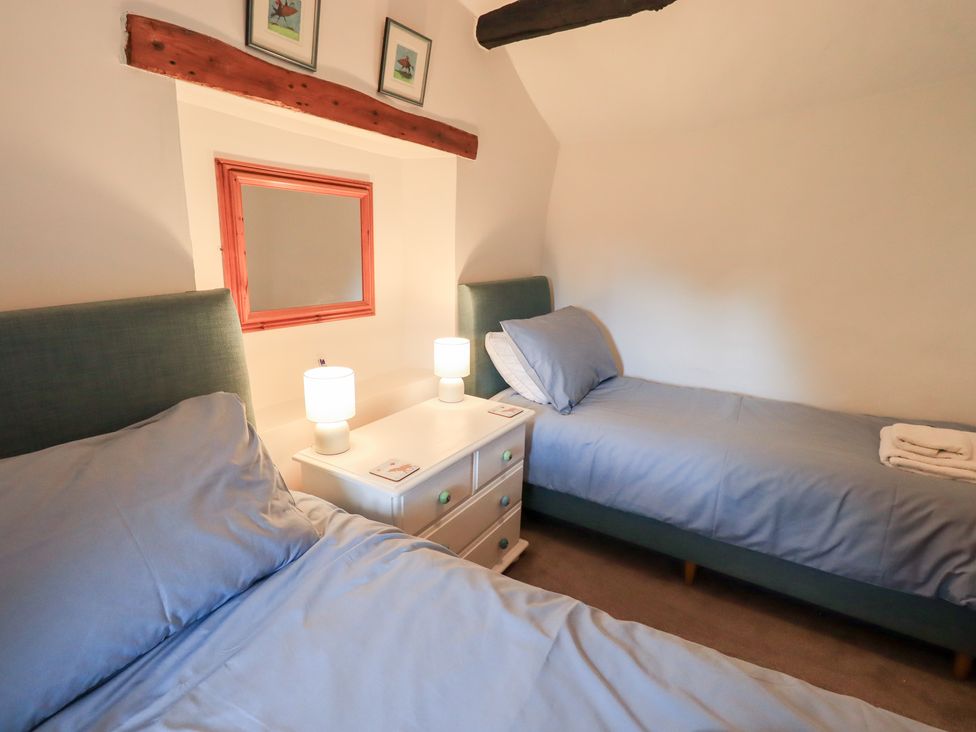 A bedroom with twin beds and a nightstand at Squirrel Cottage in Bassenthwaite