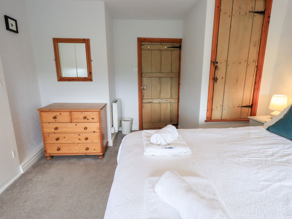 A bedroom with a bed and dresser at Squirrel Cottage in Bassenthwaite
