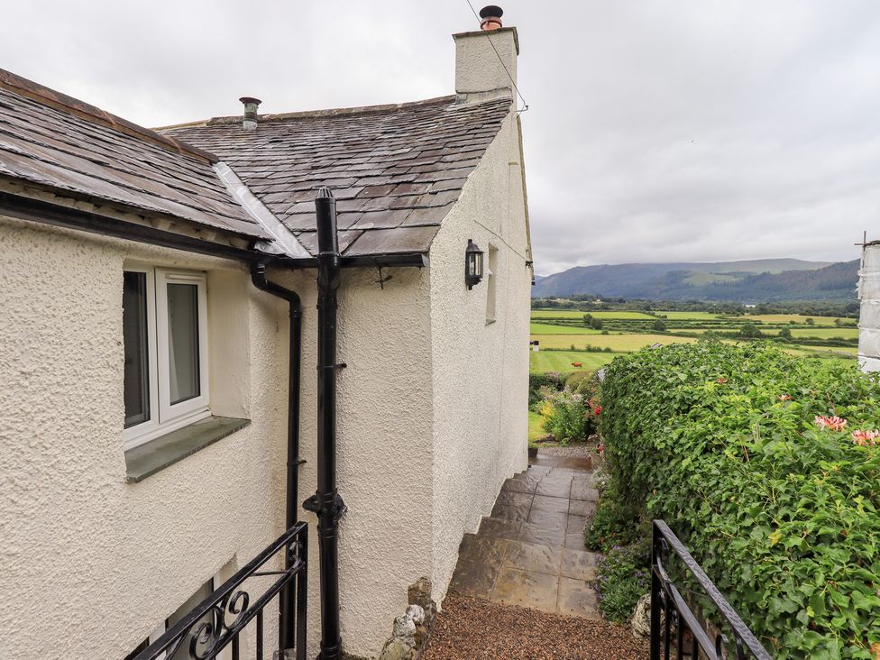 An exterior view of a house with a pathway and vegetation at Squirrel Cottage in Bassenthwaite