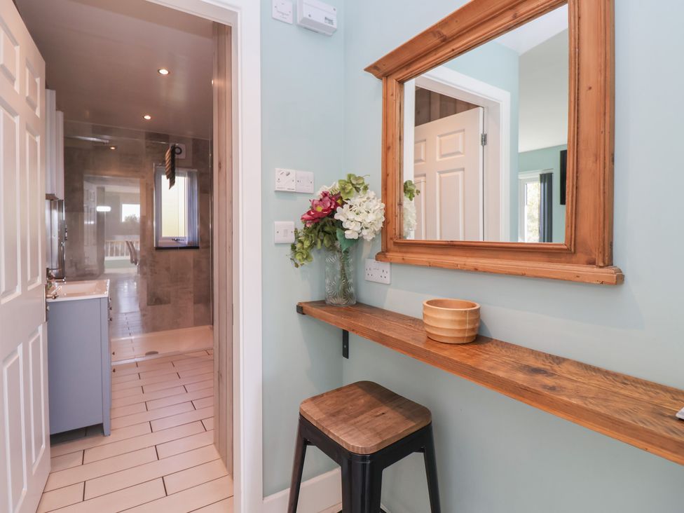 A bathroom with a wooden shelf and flower vase at Meadowbank Lodge in Brandesburton