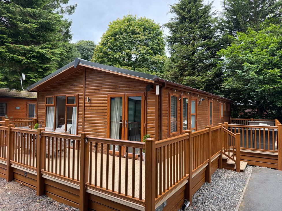 A wooden lodge with a deck and railing at Cherry Tree Lodge, Calgarth 37, White Cross Bay near Windermere