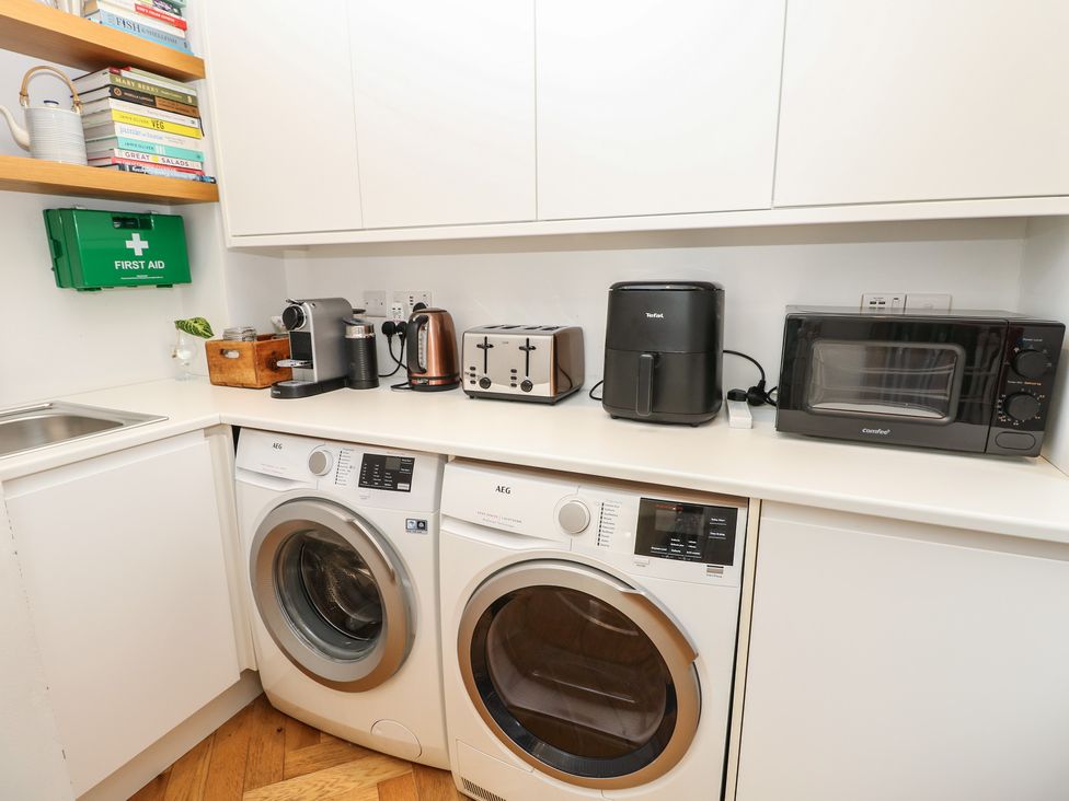 A laundry room with washing machine, dryer and kitchen appliances at Aquanaut in Gurnard