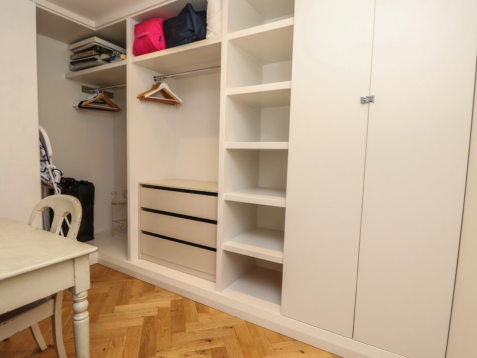 A wardrobe with shelves and a chair at Aquanaut in Gurnard