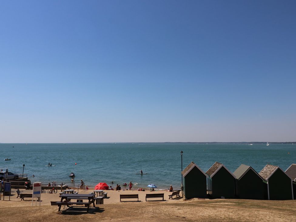 A beach scene with people swimming and beach huts at Aquanaut in Gurnard