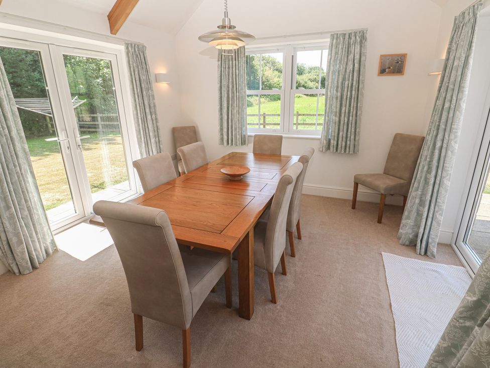 A dining room with a wooden table and eight chairs at Ilgram in St Newlyn East