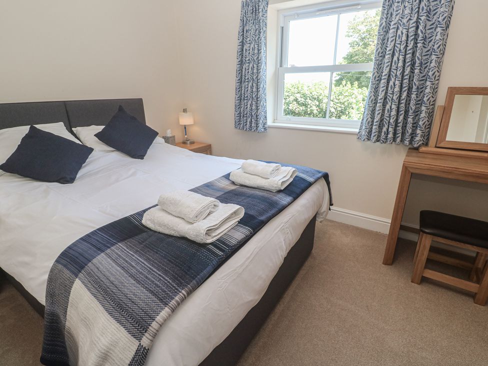 A bedroom with a bed, dressing table, and window at Ilgram in St Newlyn East