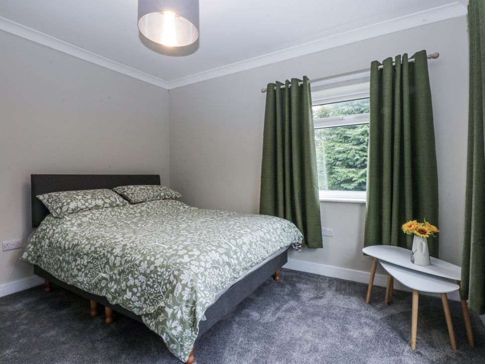 A bedroom with a bed and a table at Caledfryn in Tyn-y-Gongl