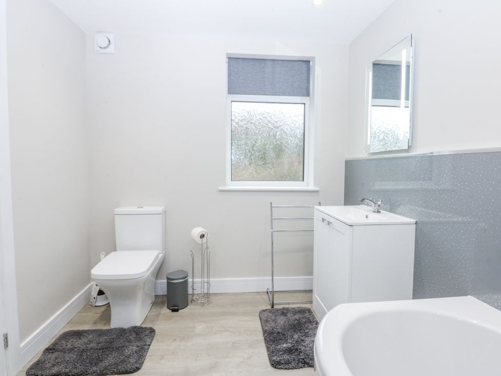 A bathroom with a toilet, wash basin, and bath tub at Caledfryn in Tyn-y-Gongl