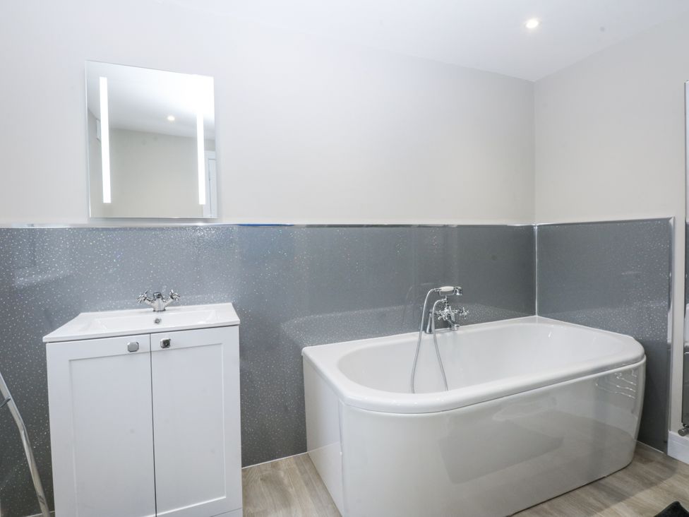 A bathroom with a bathtub and a vanity sink at Caledfryn Tyn-y-Gongl