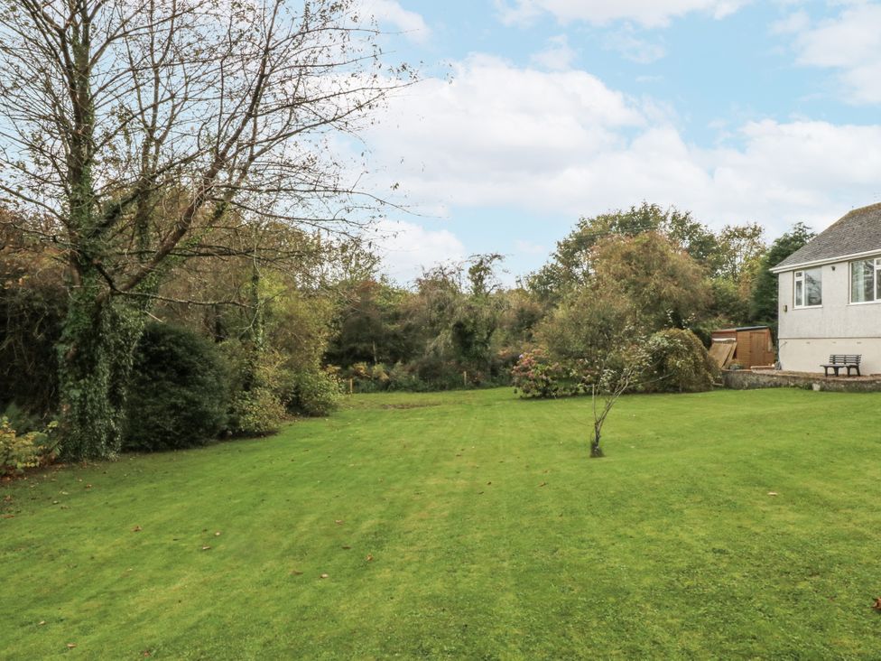 A garden with grass and trees at Caledfryn in Benllech