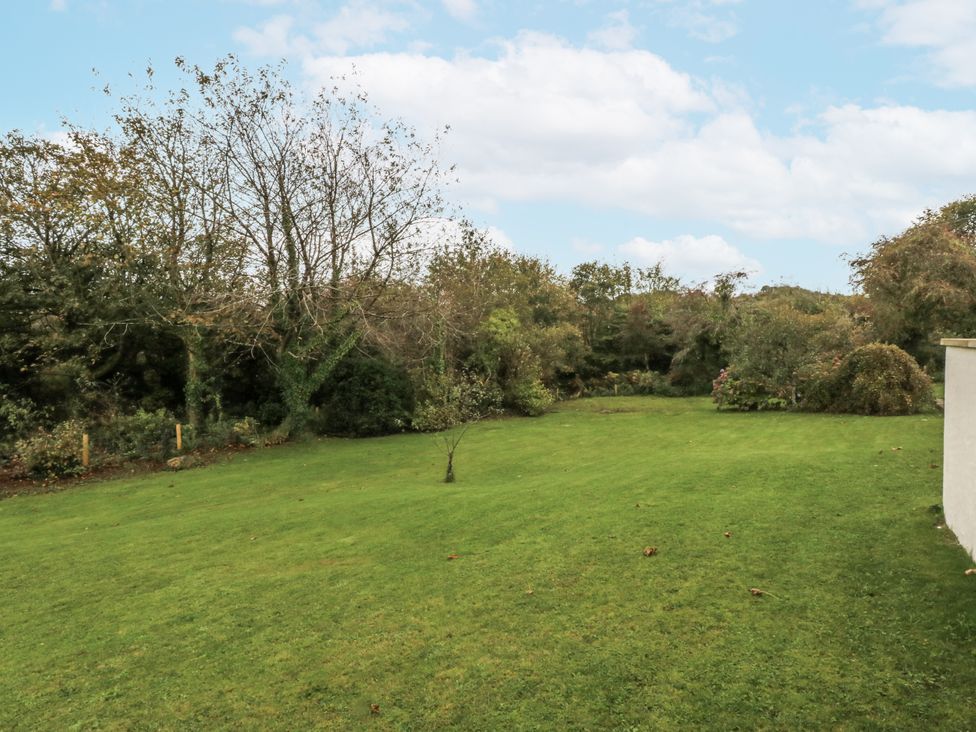 A garden with grass and trees at Caledfryn in Benllech