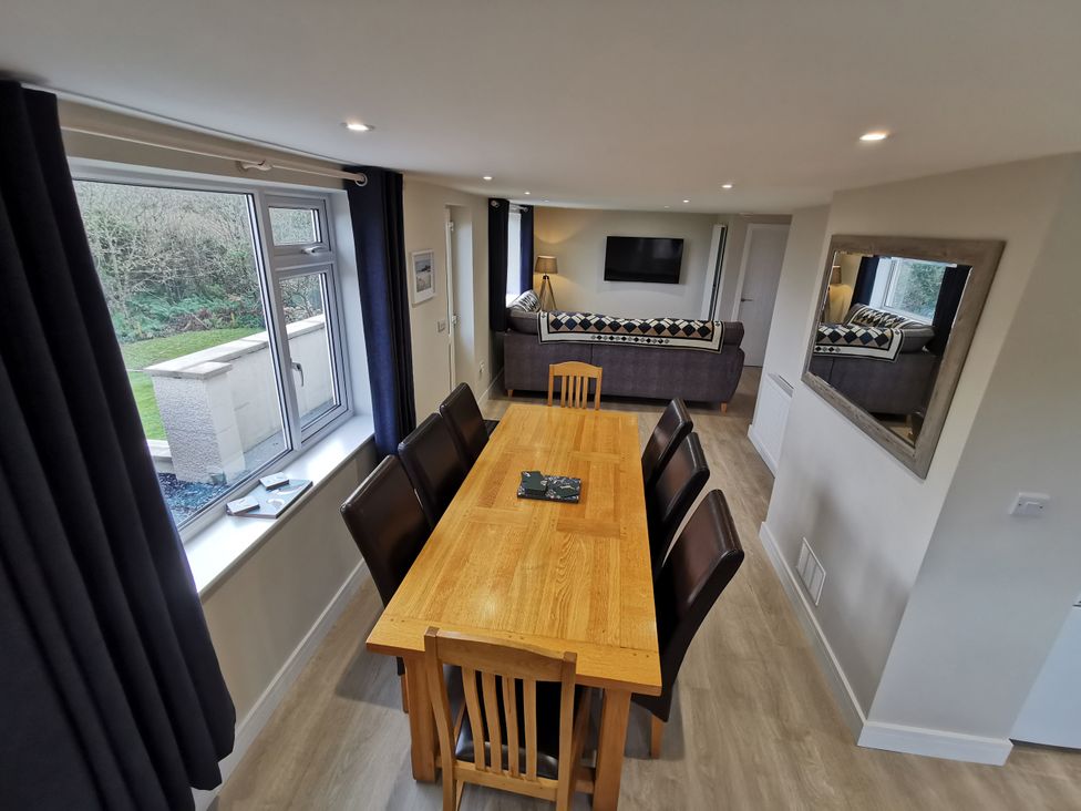 A dining room with a table and chairs at Caledfryn Benllech