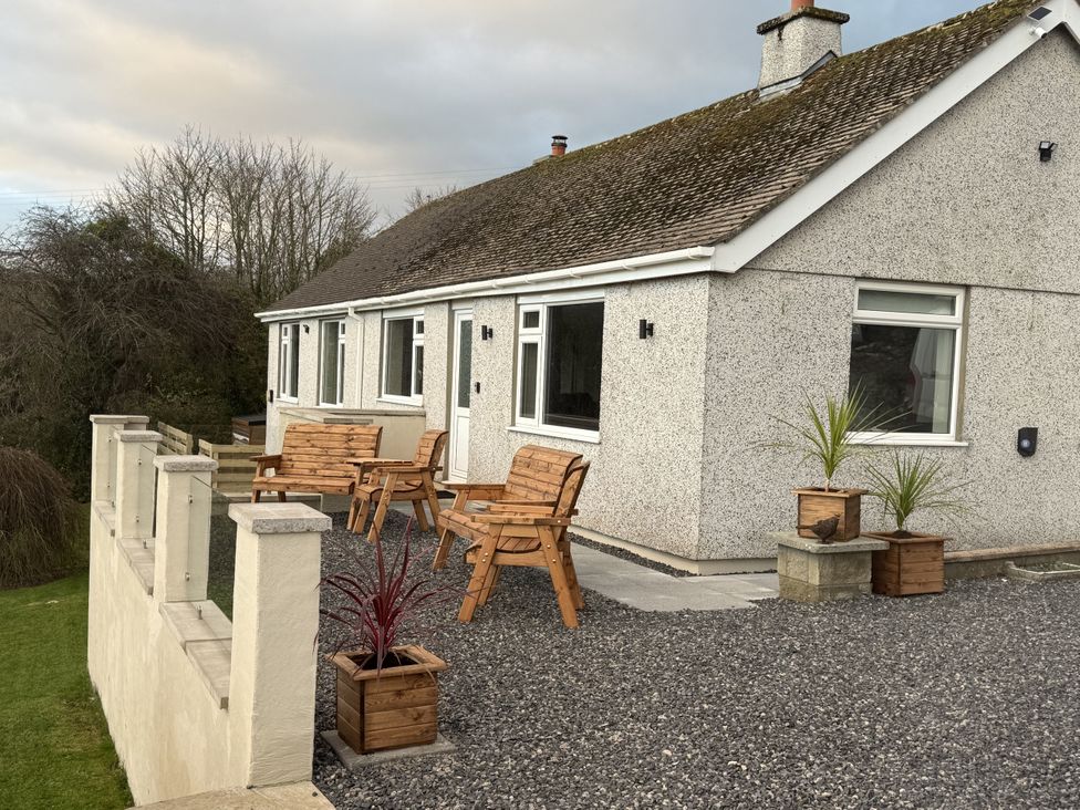 A house with chairs and planters at Caledfryn Benllech