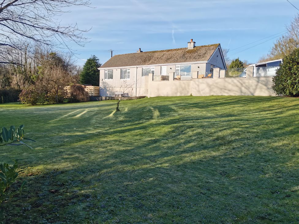 A house with a lawn and trees at Caledfryn in Benllech