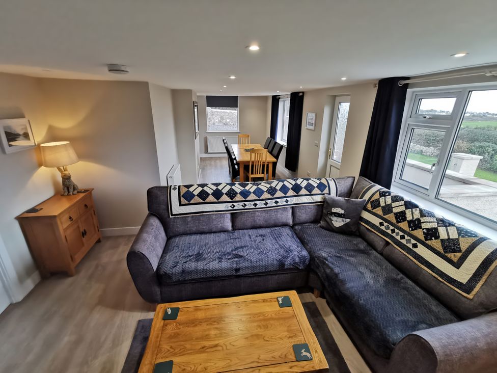 A living room with a sofa and dining area at Caledfryn in Benllech
