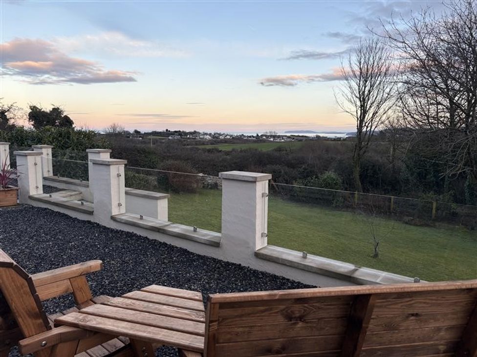 An outdoor area with wooden chairs and a view at Caledfryn in Benllech