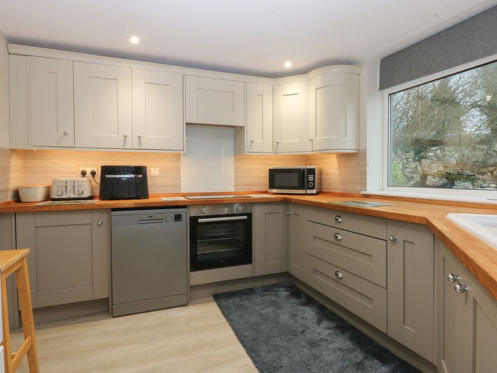 A kitchen featuring cabinets, a refrigerator, and appliances at Caledfryn in Benllech