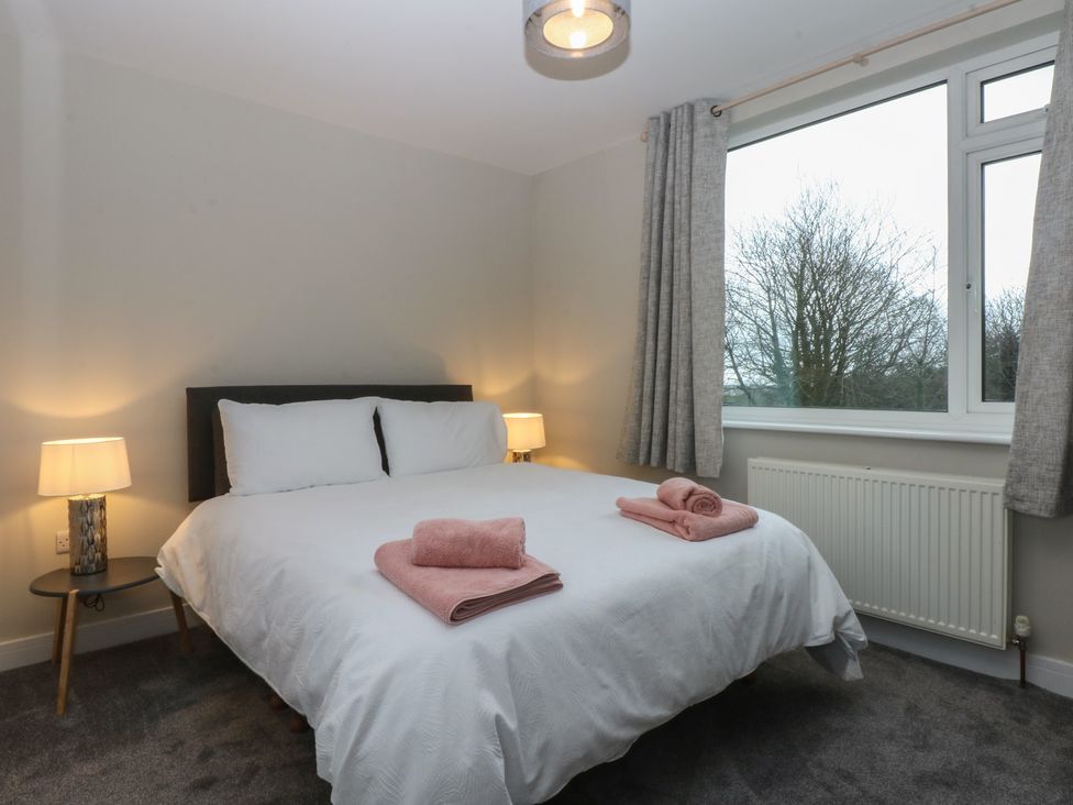 A bedroom with a bed and lamps at Caledfryn Benllech