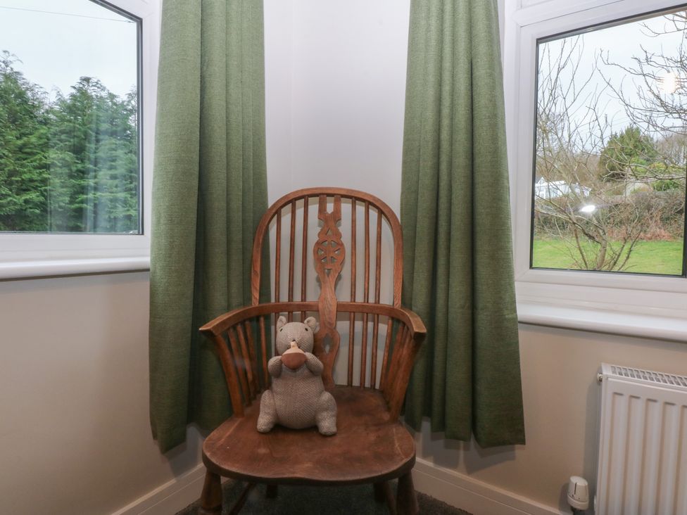 A snug with a wooden chair and a stuffed animal at Caledfryn in Benllech