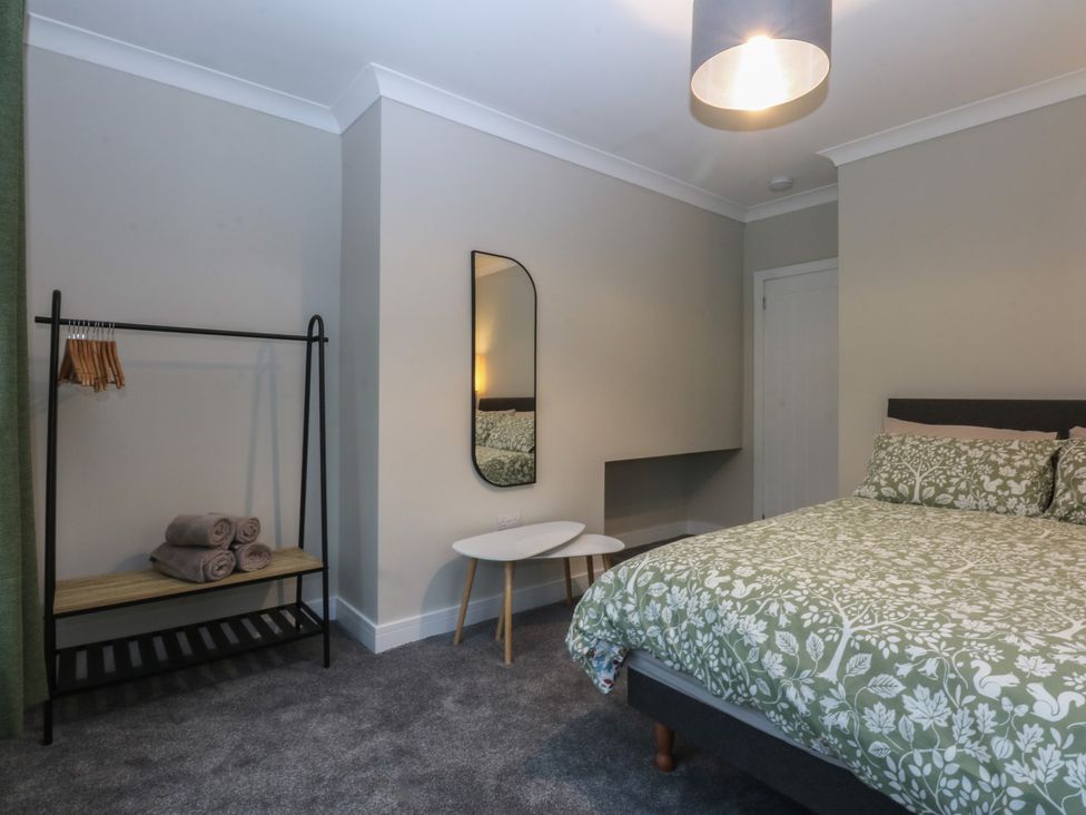 A bedroom with a bed and a mirror at Caledfryn in Benllech