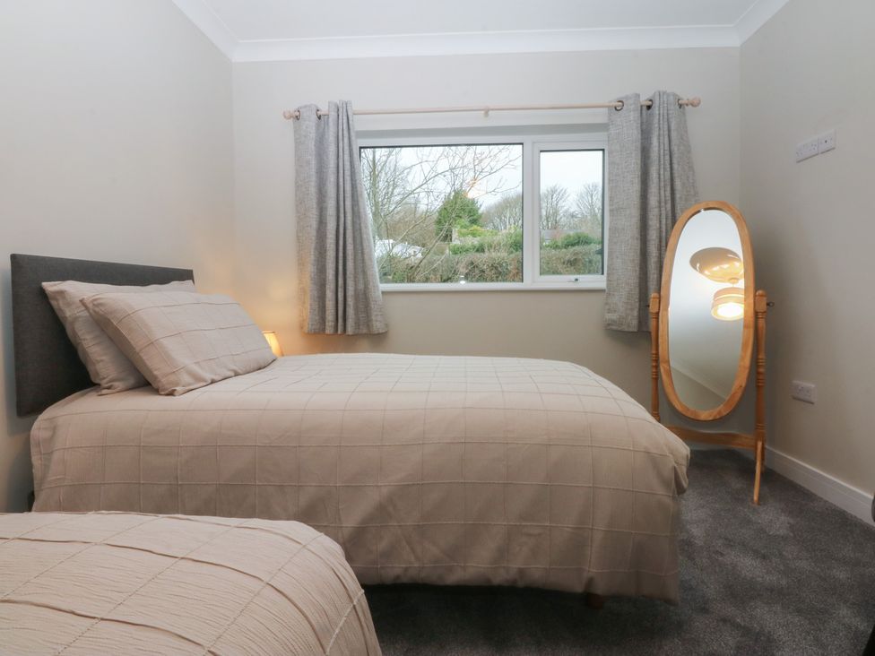 A bedroom with a bed and a mirror at Caledfryn in Benllech