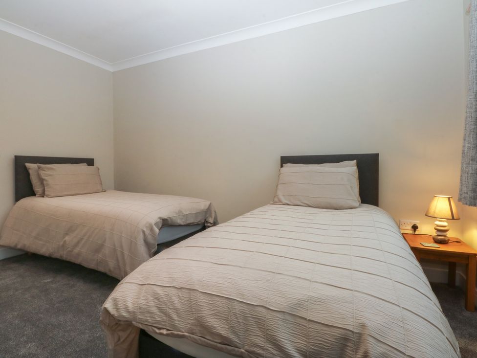 A bedroom with two beds and a lamp at Caledfryn in Benllech