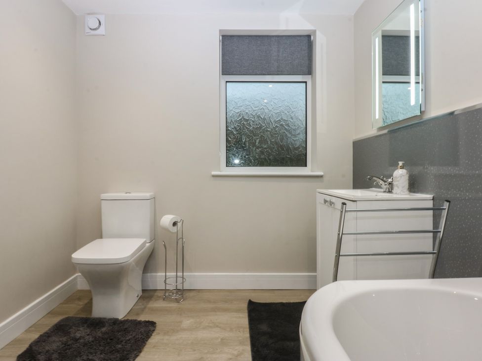 A bathroom with a bathtub, sink, and toilet at Caledfryn Benllech