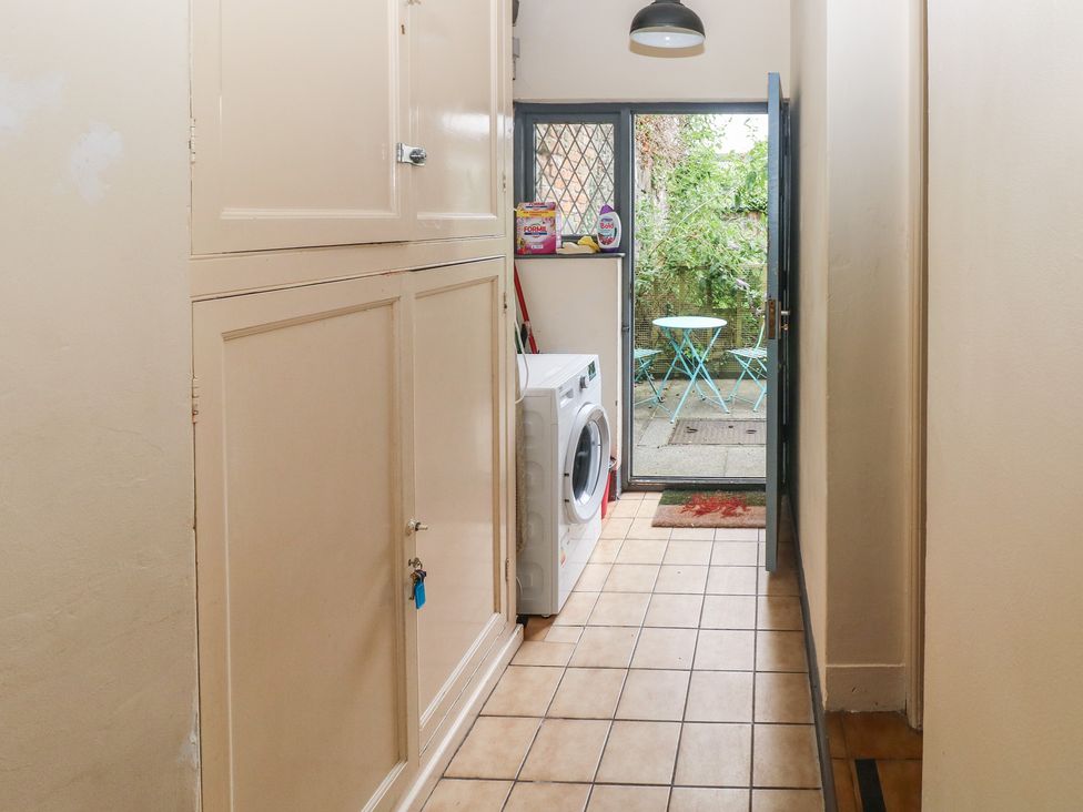 A laundry room with a washer and door leading to outdoor seating at Llys-Yr-Onnen in Carmarthen