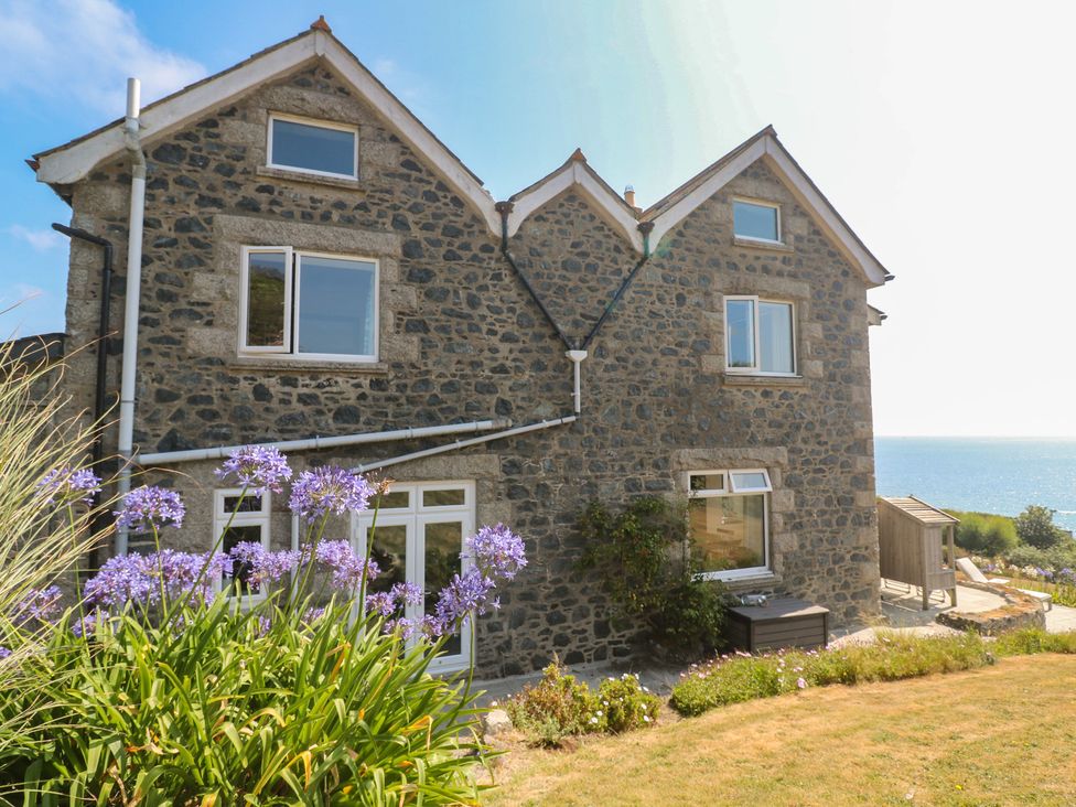 A house with stone exterior and windows overlooking the sea at Penmarth House Coverack