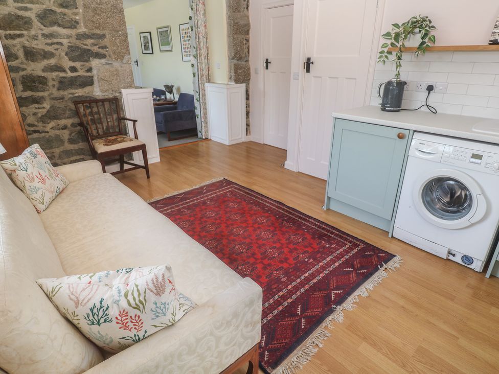 A living room with a sofa and washing machine at Penmarth House Coverack