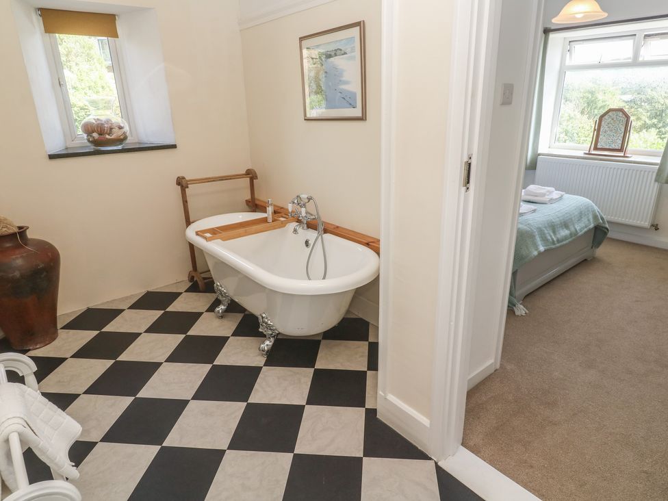 A bathroom with a bathtub and window at Penmarth House in Coverack
