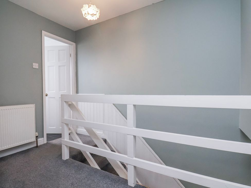 A hallway with a light fixture and staircase at 34 Fountain Close in Whitby